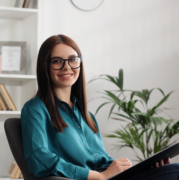 Happy,Professional,Psychologist,Woman,Sitting,In,Chair,Writing,On,Clipboard,